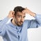 Focused young bearded man combing his hair looking at camera