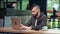 Focused young freelancer man with trendy hairstyle working on laptop pc sitting at public cafe place