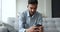 Focused young Indian man typing on smartphone at home