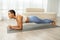 Focused young latin lady in sportswear doing plank static exercises on mat