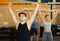 Focused young man in activewear exercising with barbell during group workout in gym health center. CrossFit healthy