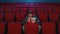 Focused young man holding a drink and popcorn basket while watching movie alone in empty theater auditorium