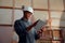 Focused young man wearing safety helmet using digital tablet in woodworking factory