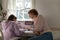 Focused young mother helping teen daughter with homework.