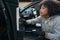 Focused young woman brushing car door panel