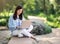 Focused young woman in casual attire working on a laptop seated on the ground in a serene park