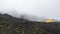 Fog covered yellow camping tent at the top of Pacaya volcano