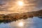 Fog and dramatic sky over a swamp with sun reflecting in a lake