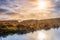 Fog and dramatic sky over a swamp with sun reflecting in a lake