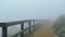 Fog and high wind rolling along a hiking trail along wooden railing