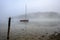 Fog on Lake Bohinj at sunrise with a red boat