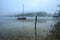 Fog on Lake Bohinj at sunrise with a red boat