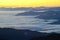 Fog lies over the mountains and yellow highlights the sky in the Smokies.