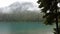 Fog obscures the mountains behind the evergreens at Jasper Lake, Alberta