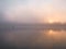 Fog over the river a fisherman in a boat at sunset in November