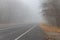 Foggy asphalt road through forest at autumn