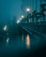 a foggy bridge at night, with street lights lit up