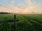 Foggy dawn on a field with rickety ruins of a fence