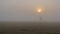 A foggy field with a sunset in the distance