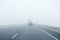 Foggy gray road, cars driving into the fog