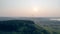 Foggy landscape with green trees and a paraglider flying above it