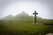 Foggy landscape with spooky stone cross and church in the background, Khvamli Mountain, Georgia.