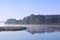 Foggy landscape with tree silhouette and reflection on water on fog at sunrise.Early summer morning on tranquil lake.Morning