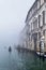 Foggy (misty) Venice. Canal, historical, houses and gondoliers with gondolas on thick fog.