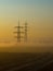 A foggy morning in an autumn field with a power line and a country road