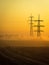 A foggy morning in an autumn field with a power line and a country road