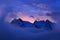 Foggy morning in Italian Alps, early morning in the mountain with snow during violet twilight, hills in the clouds