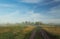 Foggy morning meadow.Summer landscape with green grass, road and clouds