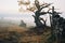 a foggy morning scene with a dead tree and a fence