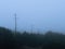 Foggy outdoor scene with power poles, hills and trails