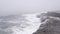 Foggy sea landscape, waves crashing on ocean beach in haze. Stormy misty weather