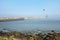 A foggy seascape with a pier and lighthouse in the background