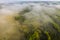 Foggy summer morning nature aerial view. Mist over green meadow with river. Misty nature landscape