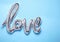 Foil LOVE word balloon on light blue, top view