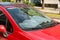 Foil sun shades covered a panel of a red car parked on the street on a sunny summer day. Reflective sun shield made of metallic