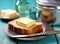 Foil wrapped processed cream cheese, table knife and slice of bread on a cutting board over blue wooden table. Small