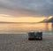 Folded beach chairs on a pebble beach against the backdrop of a calm clean sea, mountains and sunset.  Summer vacation at sea