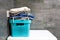 Folded bedding, jeans, towels on a blue box against the background of gray concrete wall tiles in the bathroom. Pile of laundry