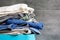 Folded bedding, jeans, towels on a blue box against the blurred background of a gray concrete wall in the bathroom