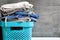 Folded bedding, jeans, towels on a blue box against the blurred background of a gray concrete wall in the bathroom