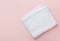 Folded clean white fluffy terry towel on pastel pink background. Minimalist flat lay. Women`s baby hygiene laundry body care