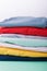 Folded colorful pants and jeans. Stack of bright female trousers. Close up.