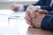 Folded male hands on a wooden table. Participant of negotiations, interviews, meetings. At the reception of a social worker,