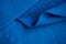 Folded piece of bright blue satin fabric isolated on white background, top view. Folds of cotton fabric. warm coat