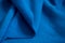 folded piece of bright blue satin fabric isolated on white background, top view. Folds of cotton fabric. warm coat. Beautiful