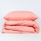 Folded pink blanket and a pillow isolated on a white background